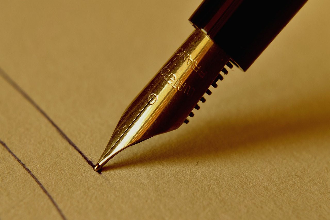 pluma dorada escribiendo en papel